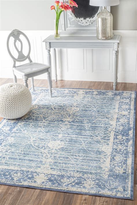 A Blue Area Rug With An Ornate Design In The Middle And A White Chair
