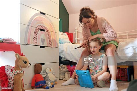 Mixed Race Mother Brushing Hair Of 7 Year Old High Res Stock Photo