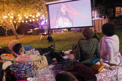Friends watching movie on projection screen in backyard - Stock Photo ...