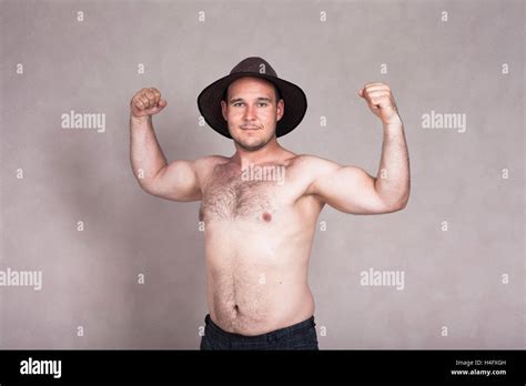 Nackter Oberkörper Mann mit Hut posiert und zeigt seine starken Arme