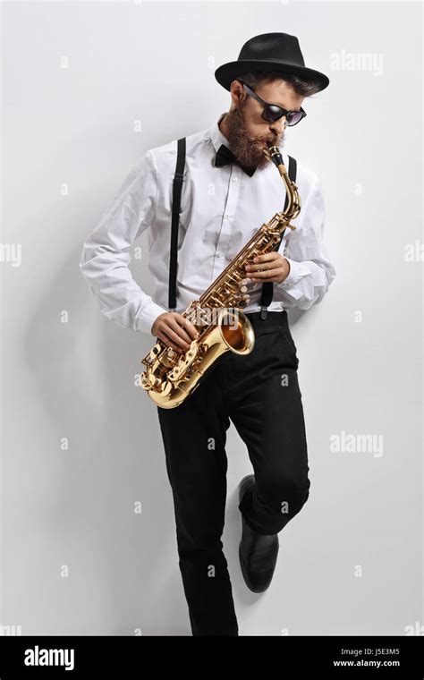 Jazz Musician Leaning Against A White Wall And Playing Saxophone Stock