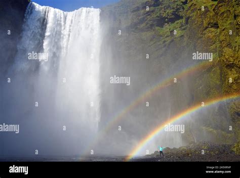 Man Stands Under Double Rainbow At The Big Waterfall Skogafoss