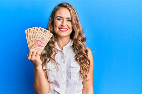 Young Blonde Girl Holding Mexican Pesos Looking Positive And Happy