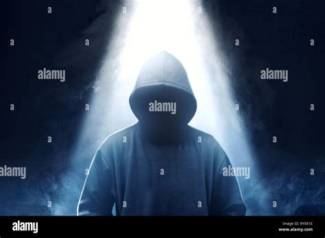Hacker In Black Hoodie Standing With Smoke And Light From The Top Over