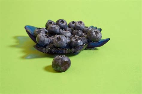 Some Blueberries Are Sitting In A Bowl On A Green Surface With The