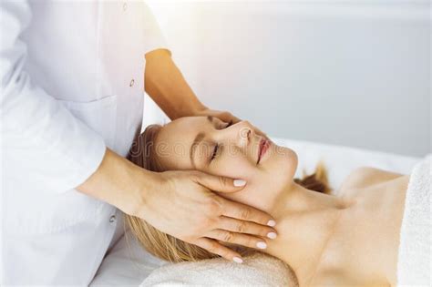 Beautiful Caucasian Woman Enjoying Facial Massage With Closed Eyes In Sunny Spa Salon Relaxing