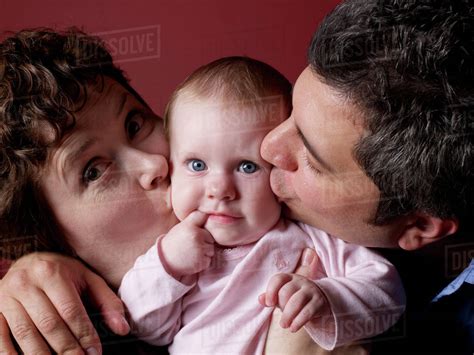 Parents Kissing Babys Cheeks Stock Photo Dissolve
