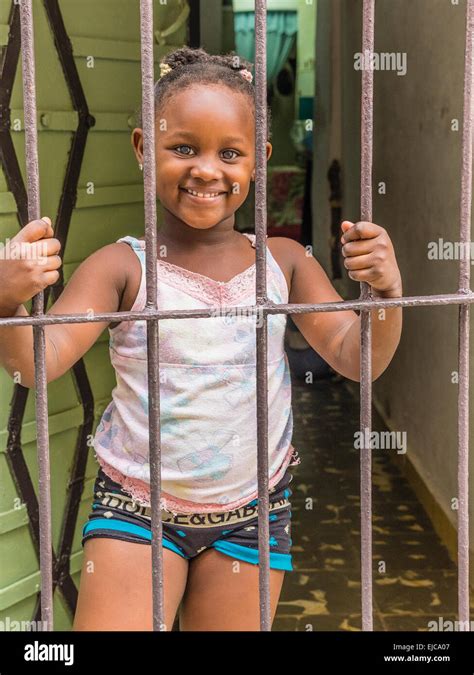 une jeune fille afro cubain détient les barreaux de la porte de sécurité de sa maison avec les