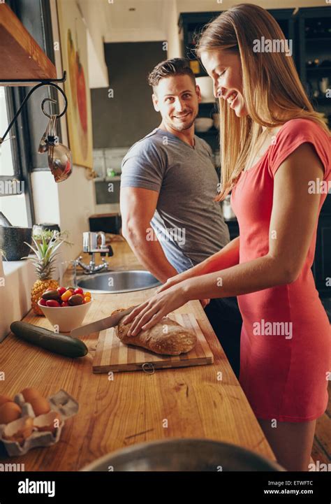 Caucasian Couple Together In The Kitchen In Morning Focus On Young Woman Cutting Bread While