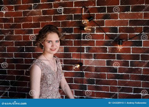 A Brunette Girl In A Beautiful Dress Posing Against A Background Of An Authentic Brick Wall