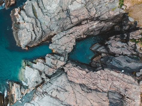 Rough Rocks Between Blue Sea Water In Daylight · Free Stock Photo