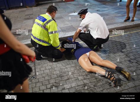 A Policeman Attending A Drunk Woman Lying On The Pavement On A Stock