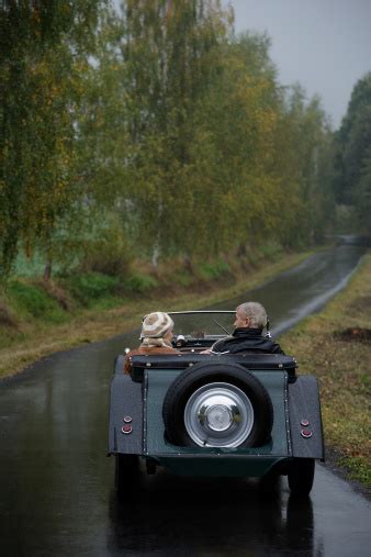 Senior Couple Driving Down Country Road In Antique Car Stock Photo