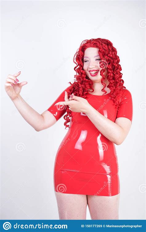 Real Doll Woman Wearing Red Latex Rubber Dress And Posing On White