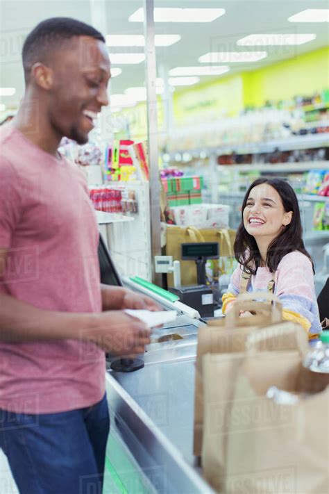 Friendly Cashier Helping Customer At Supermarket Checkout Stock Photo