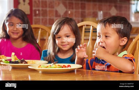 Children Eating Dinner At Table Together Stock Photo Alamy