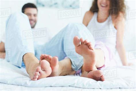 Close Up View Of Feet Of Happy Young Couple On Bed At Morning Stock