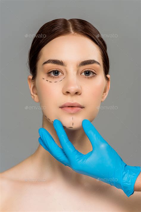Cropped View Of Plastic Surgeon In Latex Glove Touching Face Of Attractive Naked Woman Isolated