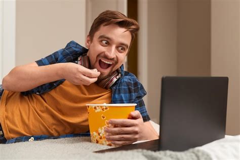 homem animado comendo pipoca e assistindo filme foto premium