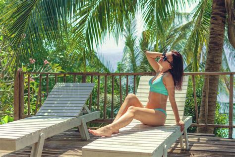 Attractive Girl Sitting In Bikini On Lounge Chair At Tropical Resort Stock Photo Dissolve