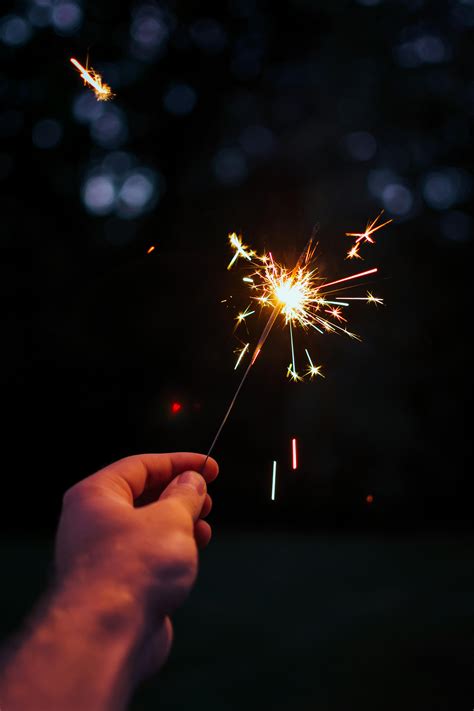 Selective Focus Photography Person Holding Lighted Sparkler At