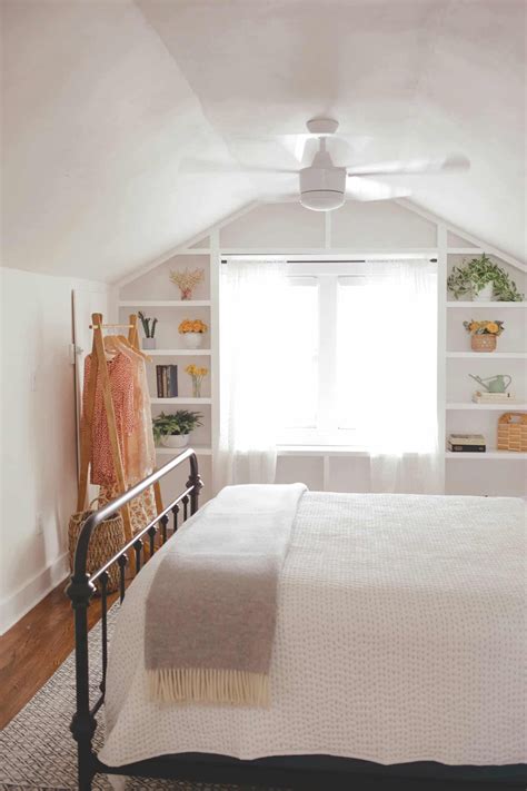 A White Bed Sitting Under A Window In A Bedroom
