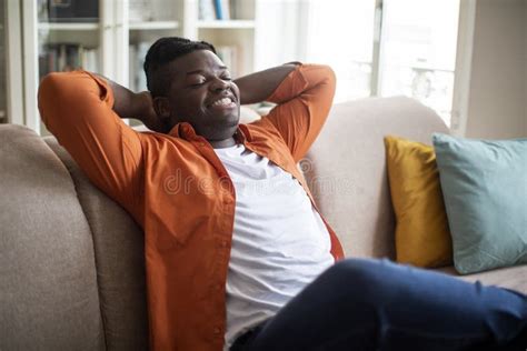 Relaxed Plus Size Black Guy Chilling On Couch At Home Stock Photo