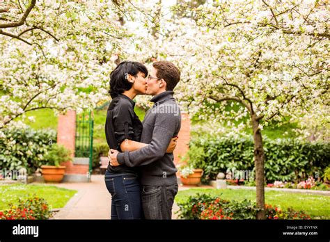 Couple Kissing Under Flowering Trees In Park Stock Photo Alamy