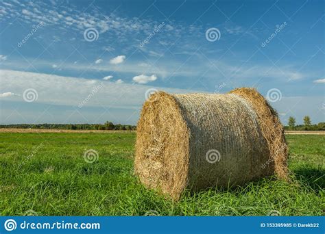 Large Hay Bale Lying On A Green Meadow Horizon And White Clouds On A