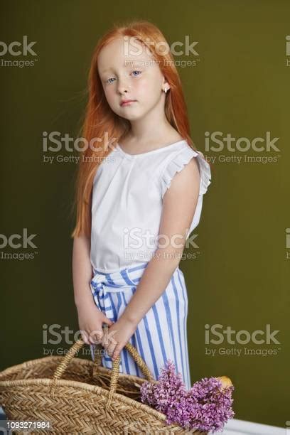 Little Redhaired Girl With A Basket Of Flowers Posing On An Olive