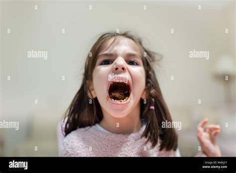 Little Cute Girl Opens Her Big Mouth And Shows Chewed Eats Chocolate With Funny Face While