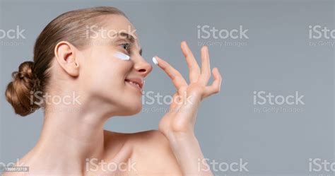 Portrait Of Young Beautiful Woman Taking Care After Skin Applying Moisturizing Cream Isolated On