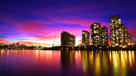 Lake And Buildings With Lights Under Blue And Purple Sky During Sunset