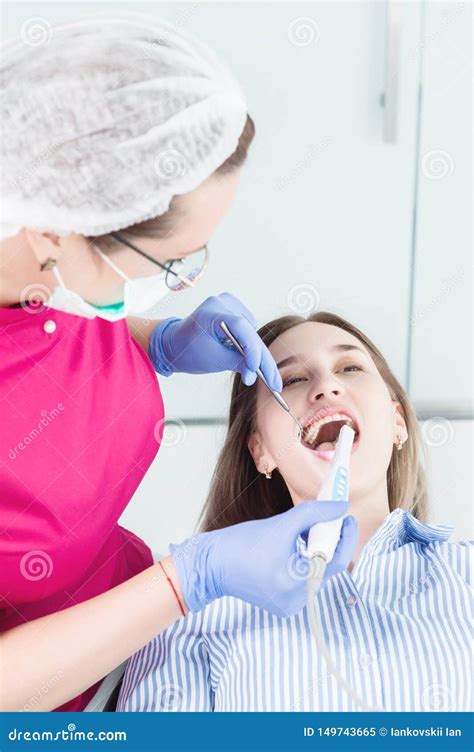 la mujer profesional del dentista del primer a en vidrios y guardapolvos examina la cavidad