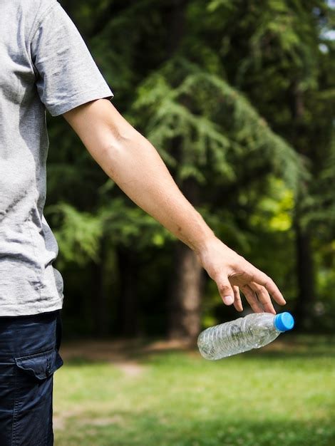 Man Hand Throwing Plastic Water Bottle In Park Free Photo