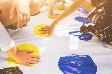Children Play A Twister On The Grass Hands On Yellow Stock Photo