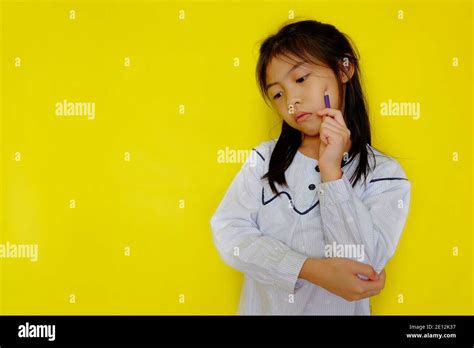 A Cute Young Asian Girl Deep In Thought With Her Hand On Her Cheek Looking Down Trying To