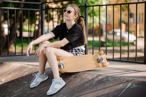 Menina Skatista Adolescente Com Um Skate Está Sentado Na Rampa No Parque De Skatistas Foto Premium