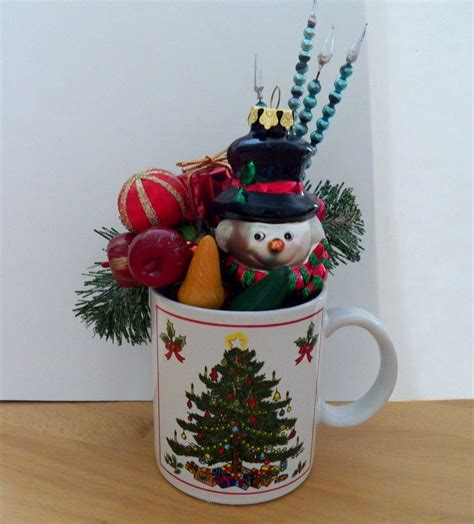 A Coffee Cup Filled With Christmas Decorations On Top Of A Wooden Table