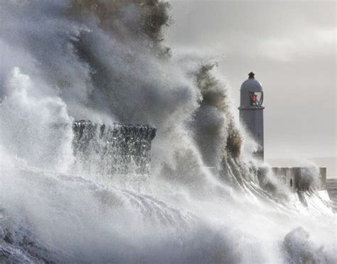 A Lighthouse Surrounded By Huge Waves In Front Of A Large Wave Crashing