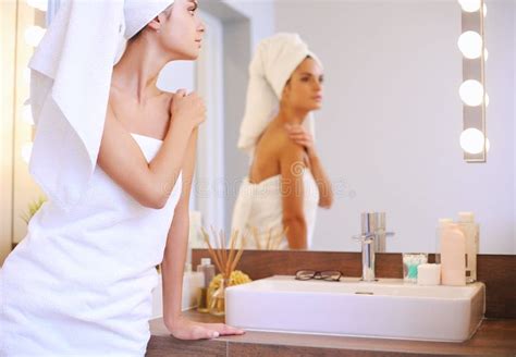 Young Attractive Woman Standing In Front Of Bathroom Mirror Stock Image