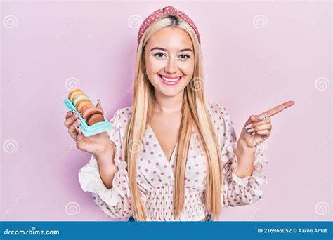 Young Blonde Girl Holding Delicious Macarons Pastries Smiling Happy Pointing With Hand And