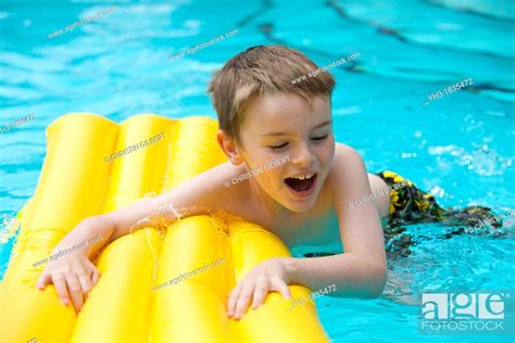 Happy Young Boy Relaxing At The Swimming Pool On A Yellow Lilo Stock