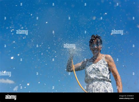Woman Spraying Water From A Hosepipe North Yorkshire Uk Stock Photo