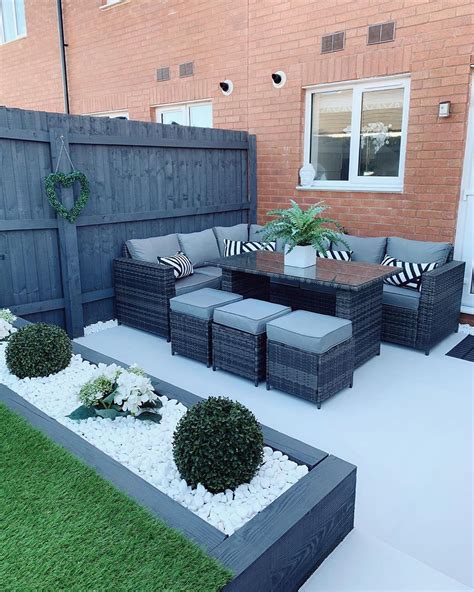 An Outdoor Living Area With Couches Tables And Potted Plants On The Grass