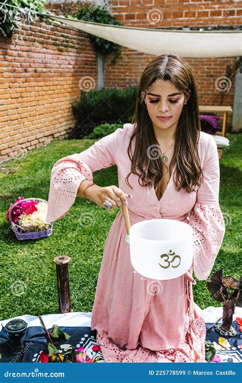 Hispanic Girl On Her Knees Playing A Quartz Singing Bowl In Holistic