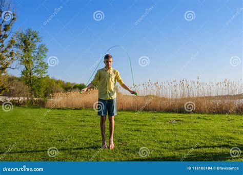Young Caucasian Boy Is Doing Workout With Jumping Rope On Green Grass