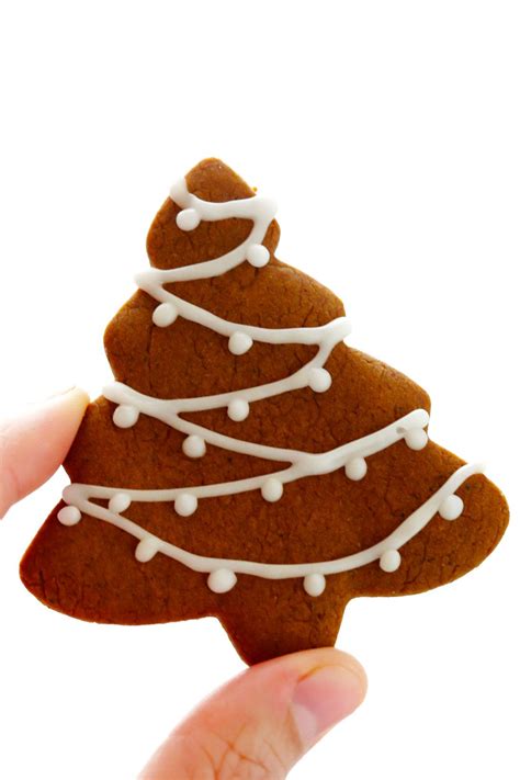 A Hand Holding Up A Cookie Shaped Like A Christmas Tree With White