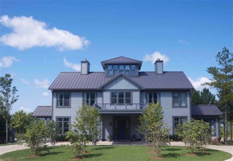 A Large Gray House Sitting On Top Of A Lush Green Field
