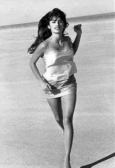 A Black And White Photo Of A Woman Running On The Beach